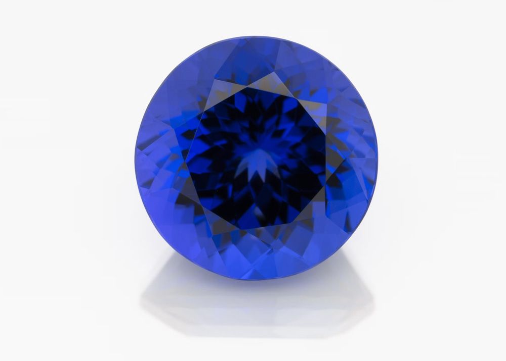 Vivid blue round tanzanite polished gemstone on white background